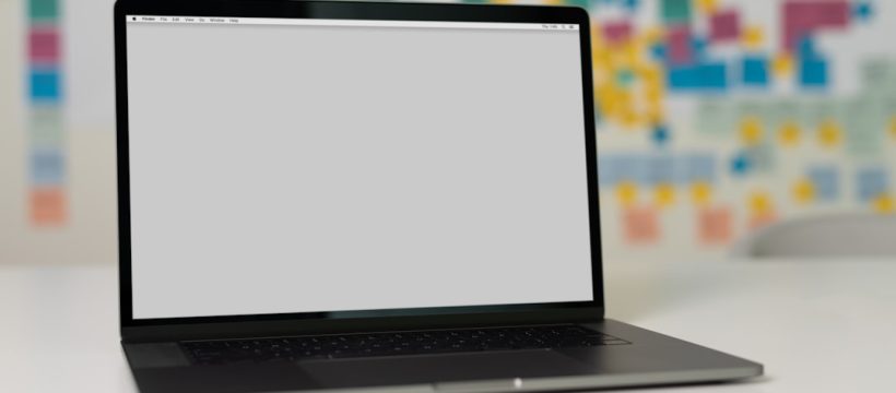 laptop on a table with a blank screen, background with colorful sticky notes